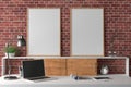 Workspace with two vertical posters mock up on the desk. Desk with drawers in interior of the studio or at home with red brick wal Royalty Free Stock Photo