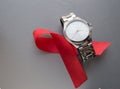 World AIDS day, red ribbon and men& x27;s WRISTWATCH on grey background, top view. solidarity in the fight against the disease