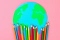 World art. Planet Earth and pencils, brushes on a pastel pink background.