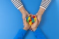 World autism awareness day concept. Female and child hands holding puzzle heart on light blue background