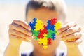 World autism awareness day concept. Boy holding colorful puzzle heart in front of his face Royalty Free Stock Photo