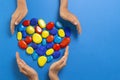 World autism awareness day concept. Children hands with heart made of blue yellow red color stones over light blue Royalty Free Stock Photo