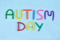 World Autism Awareness Day concept - multicolored letters made of play-doh or other sensory playfoam on blue background. Autism