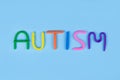 World Autism Awareness Day concept. Multicolored letters made of play-doh or other sensory playfoam on blue background