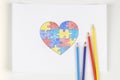 World autism awareness day concept. Puzzle heart colored with pencils on sheet of paper. Top view Royalty Free Stock Photo