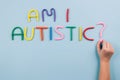 World Autism Awareness Day concept, symptoms - multicolored letters, Am I Autistic - on light blue background with child