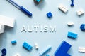 World Autism Awareness Day. Flat lay the white word AUTISM with cubes, puzzles, colored markers and toys Royalty Free Stock Photo