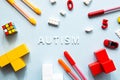 World Autism Awareness Day. Flat lay the white word AUTISM with cubes, puzzles, colored markers and toys Royalty Free Stock Photo