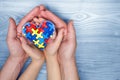 World Autism Awareness day, puzzle or jigsaw pattern on heart with autistic child`s and father hands