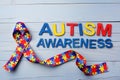 World Autism awareness and pride day or month with Puzzle pattern ribbon on blue wooden background.