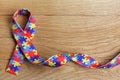 World Autism awareness and pride day or month with Puzzle pattern ribbon on wooden background.