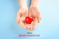 World Blood Donor Day. Woman holding red heart on light blue background, top view
