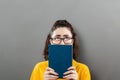 World Book Day. A portrait of a young thoughtful woman in glasses holding a book, looking up, covering half of her face Royalty Free Stock Photo