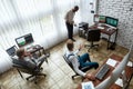 A world of business. High-angle view of three traders having chat while sitting by desks in front of computer monitors