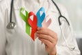 World cancer day. Close up of young female doctor holding small colorful ribbons, blue, red, green, pink for supporting people Royalty Free Stock Photo