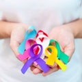 World cancer day, February 4. Hand holding blue, red, teal, white, pink, purple and yellow ribbons for supporting people living