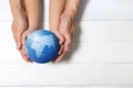 World concept: Two human hands holding global on wooden background. Royalty Free Stock Photo