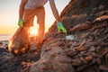 World environment day. Man volunteer picks up a plastic bottle on the beach. Close up. Wild beach on the background. The