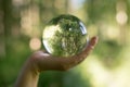 World environmental concept. Crystal globe in human hand on beautiful green and blue bokeh Royalty Free Stock Photo