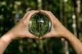 World environmental concept. Crystal globe in human hand on beautiful green and blue bokeh Royalty Free Stock Photo