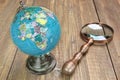 World Geographical Globe And Magnifier On The Wooden Table Royalty Free Stock Photo