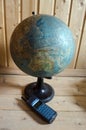 World geographical globe and retro cellphone on the wooden background