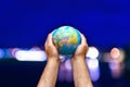 The world globe Earth in the hands of man against the blue sky night blurry city Royalty Free Stock Photo