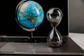 World globe with laptop and hourglass close-up. Online business and world trade concept Royalty Free Stock Photo