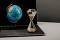 World globe with laptop and hourglass. Online business and globalisation theme