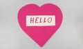 World Greetings Day. The day of winning friends. The word hello and a pink heart cut out of paper on a white background
