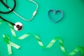 World health day background, Healthcare and medical background concept of Stethoscope with heart ribbon on green paper background