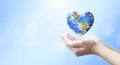 Holding Earth in heart shape hands against natural background, Elements of this image furnished by NASA Royalty Free Stock Photo