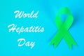 World Hepatitis Day. June 28th. Jade green ribbon on a blue table.