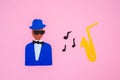 World Jazz Day. Silhouette of a musician with a saxophone on a pink background, cutted out of felt. Flat lay