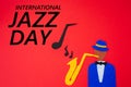 World Jazz Day. Silhouette of a musician with a saxophone from which melodies flew out, on a red background, cutted out of felt.