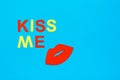 World Kiss Day. Red lips and the inscription kiss me from colored cardboard on a blue background