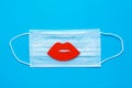 World Kiss Day. Red lips on a protective medical mask on a blue background. Coronavirus pandemic