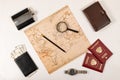 World map, pencil, magnifying glass, two passports, diary, black wallet with money and a flask on a wooden table. inscriptio