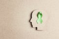 World mental health day concept. Green awareness ribbon with brain symbol on a brown background