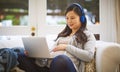 The world online is filled with so much knowledge. a pregnant woman wearing headphones while using a laptop at home.