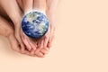 World in our hands. Top view of parents and kid holding digital model of Earth on beige background, space for text Royalty Free Stock Photo