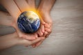 World in our hands. Top view of parents and kid holding digital model of Earth on wooden background, space for text Royalty Free Stock Photo