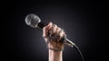 World press freedom day concept. Hand holding a microphone with chain on dark background, symbol of press freedom or speech