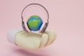 World Radio Day. a hand on which the planet is in headphones on a pastel background. 3D render