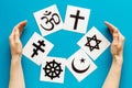 World religions concept. Hands hugs Christianity, Catholicism, Buddhism, Judaism, Islam symbols on blue background top