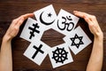 World religions concept. Hands hugs Christianity, Catholicism, Buddhism, Judaism, Islam symbols on wooden background top
