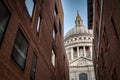 World renowned landmark that is St. Paul Cathedral seen from a narrow alley enclosed by two brick buildings on a sunny day of Royalty Free Stock Photo