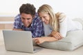The world at their finger tips. A happy young couple lying on the floor at home and using a laptop together. Royalty Free Stock Photo
