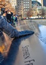 World Trade Center Memorial at Ground Zero, Manhattan. A girl, putting his hand on the bronze parapet.