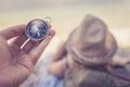 Travel around the world: compass in foreground, beautiful girl with straw hat lying on the beach in the background